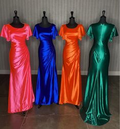 four different colored dresses on mannequins in front of a wall and floor