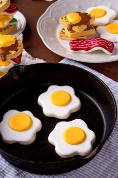 three fried eggs are in a cast iron skillet on a table with other breakfast foods