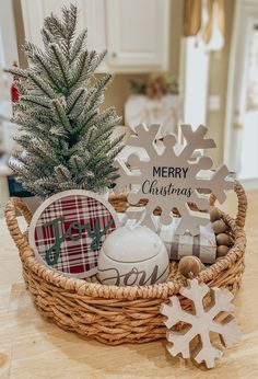 a basket filled with christmas decorations on top of a wooden table next to a small tree