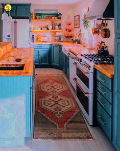 a kitchen with blue cabinets and an area rug on the floor in front of the stove