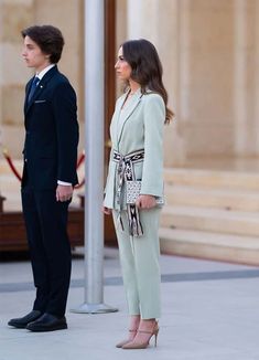 a man and woman standing next to each other in front of a building with columns