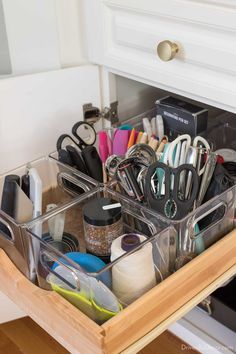 an organized drawer with scissors, pens and other office supplies in the bottom compartment for storage