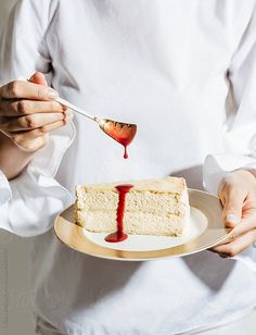 a person holding a plate with a piece of cake on it and a spoon in their hand