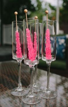 three wine glasses with pink candles in them sitting on a table next to each other