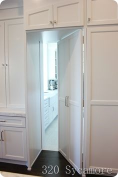 an open door leading into a kitchen with white cupboards and drawers on either side