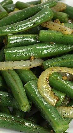 green beans and onions on a white plate with seasoning sprinkled around them