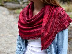 a woman wearing a red knitted shawl in front of some rocks and trees