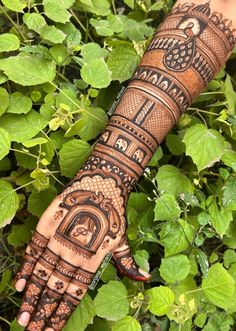 a person's hand with henna tattoos on it and green leaves in the background