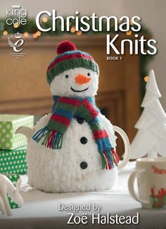 a knitted snowman sitting on top of a table next to a cup and saucer