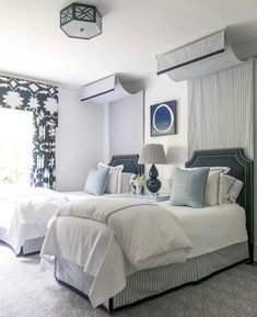 two beds in a bedroom with blue and white decor