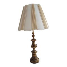 a lamp that is on top of a white table cloth with a light shade over it