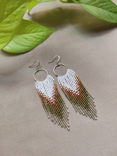 Step into the realm of timeless elegance with our "Demeter's Harvest Fringe Earrings". Handcrafted with love & precision, these earrings feature a palette of shimmering Miyuki beads in a harmonious blend of crystal white, sun-kissed gold & earthy hues of green. Their intricate brick stitch design, reminiscent of ancient Greek mosaics, adds a touch of elegance & sophistication. As these earrings dance gracefully with every movement, they radiate an aura of ethereal beauty that will captivate all White Teardrop Hoop Earrings With Dangling Beads, White Teardrop Jewelry For Celebration, Bohemian Style White Single Earring, Bohemian Round Beads Earrings For Wedding, White Hoop Earrings For Pierced Ears For Celebration, Handmade Chandelier Earrings For Anniversary, White Drop Earrings For Celebration, Bohemian Round Bead Wedding Earrings, Handmade Multicolor Bridal Earrings Gift