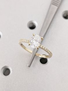 a white diamond ring sitting on top of a metal object with holes in the background