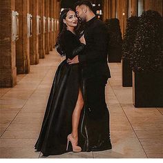 a man and woman standing next to each other on a tiled floor with columns in the background