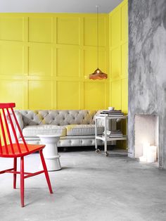 a red chair sitting in front of a yellow wall next to a white couch and fire place