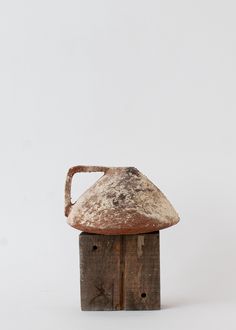 an old rusted metal jug sitting on top of a wooden block with holes in it