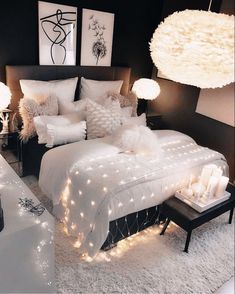 a bedroom decorated in white and grey with lights on the bed