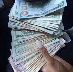 a person is holding money in their hand and pointing to it on top of them