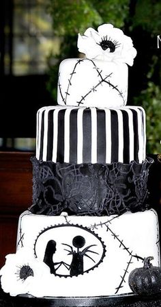 a three tiered cake decorated with black and white stripes, skulls, and flowers