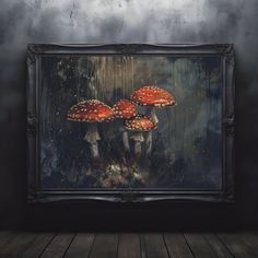 three red mushrooms sitting on top of a wooden floor in front of a framed painting