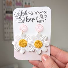 Brighten up your look with these Large Daisy Statement Earrings. Featuring big white and yellow flowers with pink glitter accents, these fun dangles are perfect for any occasion. Handmade from polymer clay with stainless steel posts, they are an ideal gift for teachers or anyone who loves bold, playful jewellery.  Details: ⭐️ Large daisy design ⭐️ Pink glitter accents ⭐️ Statement dangles ⭐️ Fun and playful style ⭐️ Handmade from polymer clay ⭐️ Stainless steel posts ⭐️ Total length is 6cm and w Spring Party White Flower Earrings, Trendy Handmade White Flower Earrings, Trendy White Handmade Flower Earrings, White Daisy Flower Earrings For Spring, White Flower Earrings For Spring, White Flower Earrings With 3d Flowers For Spring, Whimsical White Earrings For Spring, White Flower Decorated Earrings For Spring, Spring White Flower Earrings With 3d Flowers