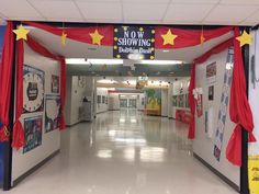 an empty hallway with red curtains and yellow stars hanging from it's ceiling in front of the door