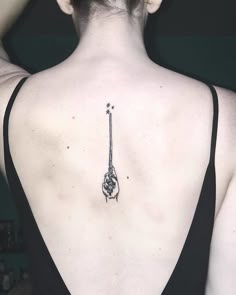 the back of a woman's neck with a tattoo on her left shoulder and an arrow in the middle