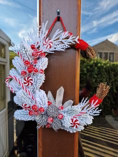 a christmas wreath hanging on the side of a door with candy canes and pine cones