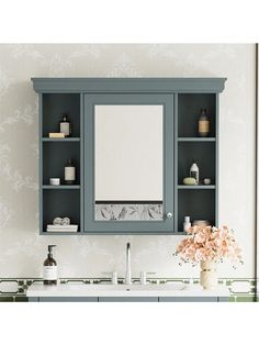 a bathroom sink with a medicine cabinet above it and a flower vase on the counter