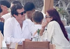 a man and woman sitting next to each other at a table with drinks in front of them