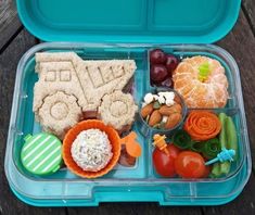 a blue lunch box filled with food on top of a wooden table next to an orange slice