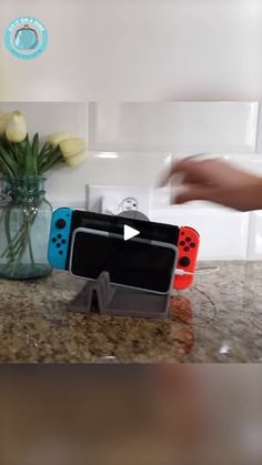 video game controllers sitting on top of a counter next to a vase filled with flowers