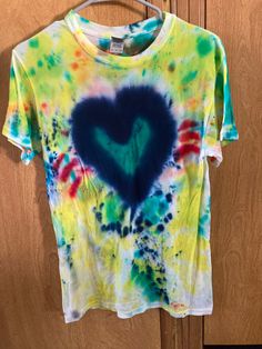 a tie - dyed shirt with a blue heart in the center on a hanger