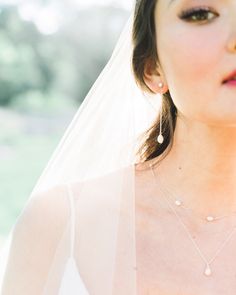 A bride wears Teardrop Pearl Long Earrings, paired with a pearl station necklace. Minimalist Teardrop Pearl Earrings With Charm, Minimalist Teardrop Pearl Charm Earrings, Delicate Teardrop Pearl Drop Dangle Earrings, Minimalist Teardrop Pearl Drop Dangle Earrings, Delicate Drop Linear Earrings For Wedding, Minimalist Teardrop Dangle Earrings With Pearl Drop, Dainty Long Drop Linear Earrings With Pearl Drop, Delicate Teardrop Pearl Drop Bridal Earrings, Delicate Pearl Drop Teardrop Bridal Earrings