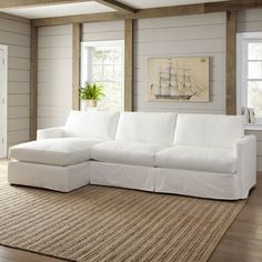 a white couch sitting on top of a rug in a living room next to a window