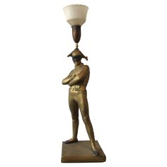 a brass statue with a lamp on it's head and a baseball cap on top