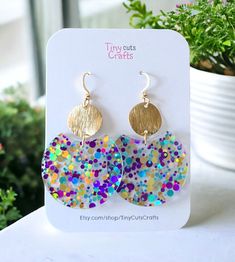 Confetti Lightweight Fun Glitter Earrings, the perfect accessory to add a pop of joy and sparkle to any outfit! Crafted with care from high-quality acrylic, these earrings are both lightweight and durable, ensuring comfort and longevity with every wear. Measuring at a delightful 1.40 inches in diameter and 2-2.25 inches in height, these round earrings boast a playful yet sophisticated design. Each earring is adorned with a mesmerizing array of vibrant confetti-style glitter and gold brass brushe Fun Gold Jewelry For Party, Glitter Hoop Earrings Gift, Hoop Jewelry With Glitter For Gifts, Multicolor Round Earrings For Birthday, Playful Gold Earrings For Party, Fun Gold Jewelry For Birthday, Multicolor Fun Hoop Earrings For Party, Fun Multicolor Hoop Earrings For Party, Fun Small Hoop Earrings As Gift