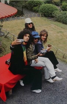 four people sitting on a red bench outside