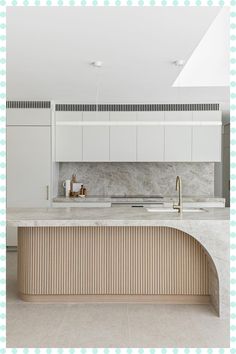 a kitchen with white cabinets and marble counter tops, along with an island in the middle