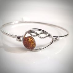 This very delicate sterling silver buckle cuff bracelet has a beautiful design in front with a small round amber bead. You would love this bracelet, nit is easy to wear and it would be a great addition to your silver jewelry collection. Bracelet Size: Bracelet measures about 2 ½ inches in diameter, Fits 6 1/4" wrist Amber color: Cognac Amber size: ⅓ inch in diameter Weight: 8 g Material: .925 sterling silver, natural amber. Made in Poland. The COGNAC AMBER IN STERLING SILVER LIGHT EARRINGS or SI Light Earrings, Buckle Bracelet, Amber Bracelet, Silver Lights, Natural Amber, Amber Beads, Amber Jewelry, Amber Color, Bracelet Sizes