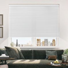 a living room filled with furniture and a window covered in white cellular shades over the windows