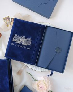 an open blue book sitting on top of a table next to flowers and other items