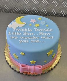 a blue cake with yellow stars and a pink bow on the top that says twinkle twinkle little star how we wonder what you are