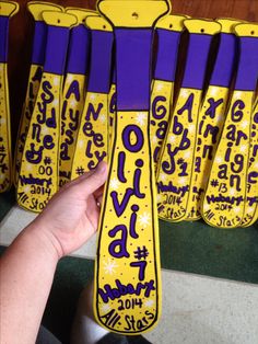 a hand is holding up some purple and yellow skis that are decorated with words