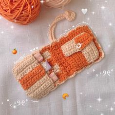 a crocheted purse sitting on top of a table next to balls of yarn