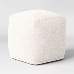 a white cube ottoman sitting on top of a floor