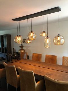 a dining room table and chairs with lights hanging from the ceiling