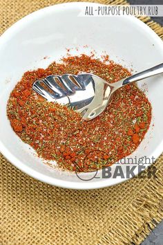 a white bowl filled with spices on top of a woven place mat next to a silver spoon