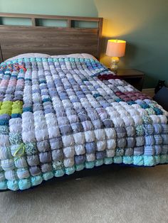 a bed covered in blankets and pillows on top of a carpeted floor next to a night stand