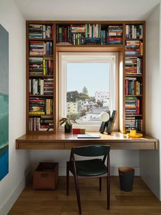 a home office with bookshelves and a desk in front of a large window